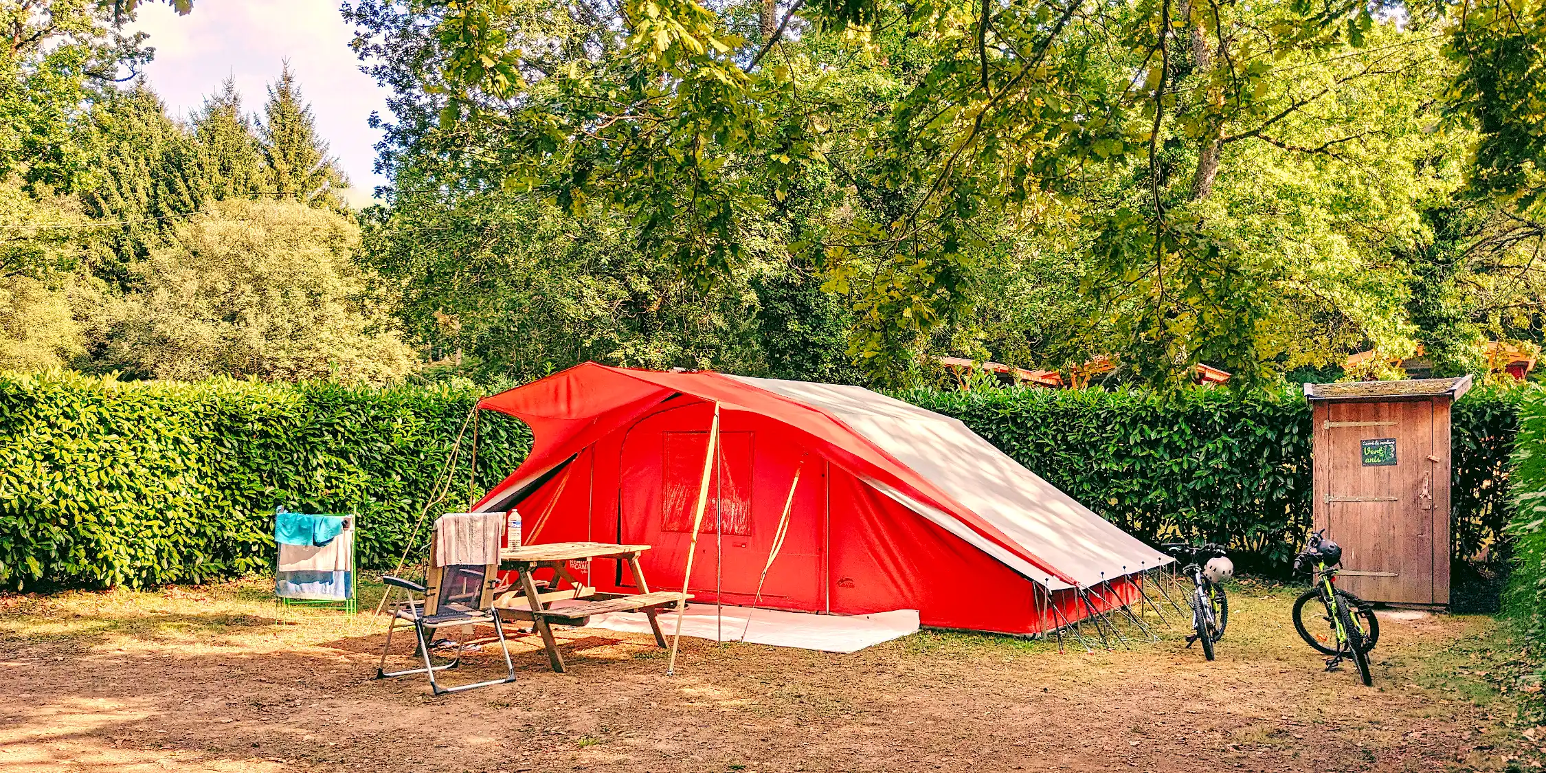 Tente installée sur un emplacement ombragé du petit camping familial Parenthèses imaginaires en Dordogne