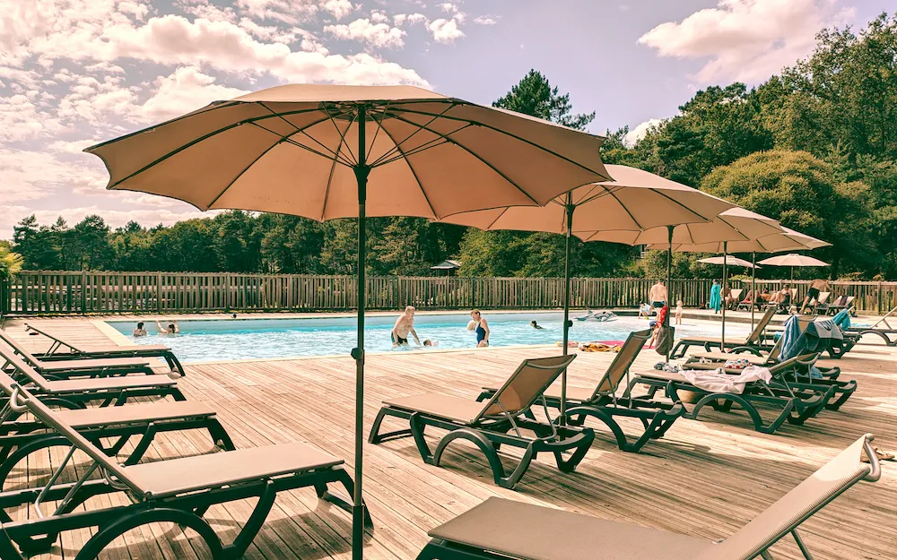 Piscine 180m² avec parasols et transats, activités aquatiques gratuites incluses au camping nature en Dordogne Périgord Vert